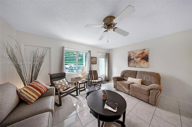 living room featuring a textured ceiling, ceiling fan, and light tile patterned floors