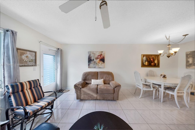 tiled living room with ceiling fan with notable chandelier and a textured ceiling