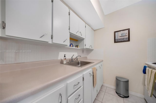 kitchen featuring white cabinetry, sink, backsplash, light tile patterned flooring, and stove