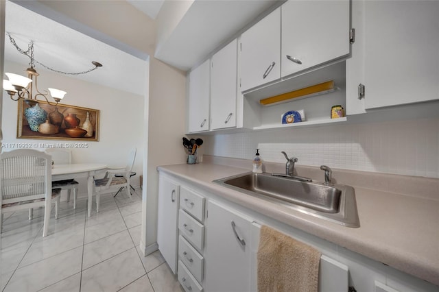 kitchen with sink, white cabinetry, light tile patterned floors, and a notable chandelier