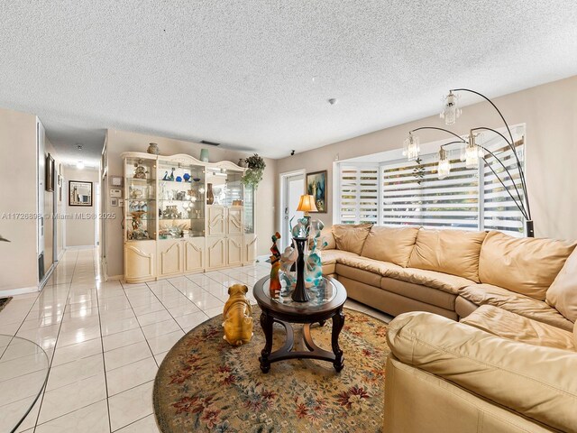 living room with a textured ceiling, light tile patterned floors, and a notable chandelier