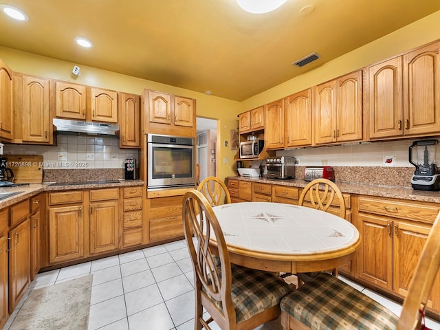 kitchen with light tile patterned floors, stainless steel appliances, and backsplash