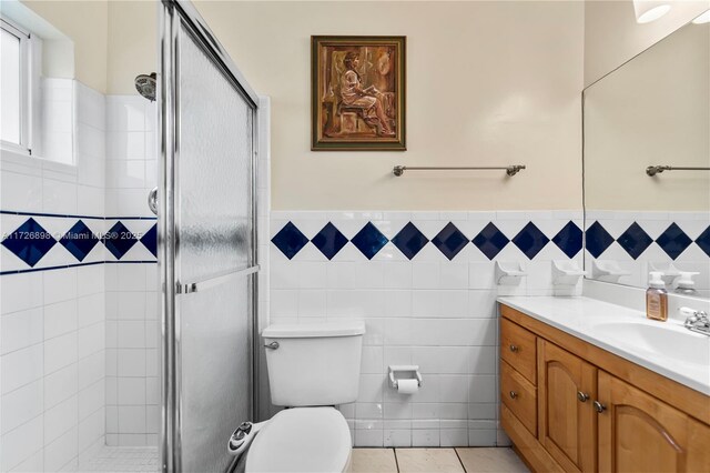 bathroom with toilet, vanity, tile walls, walk in shower, and tile patterned floors