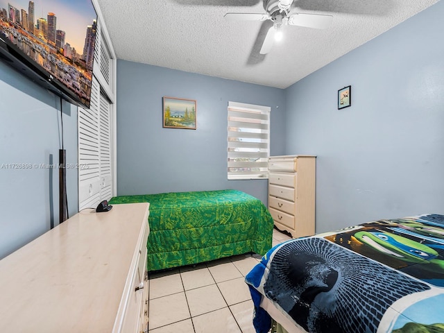 bedroom featuring ceiling fan, a textured ceiling, and light tile patterned flooring