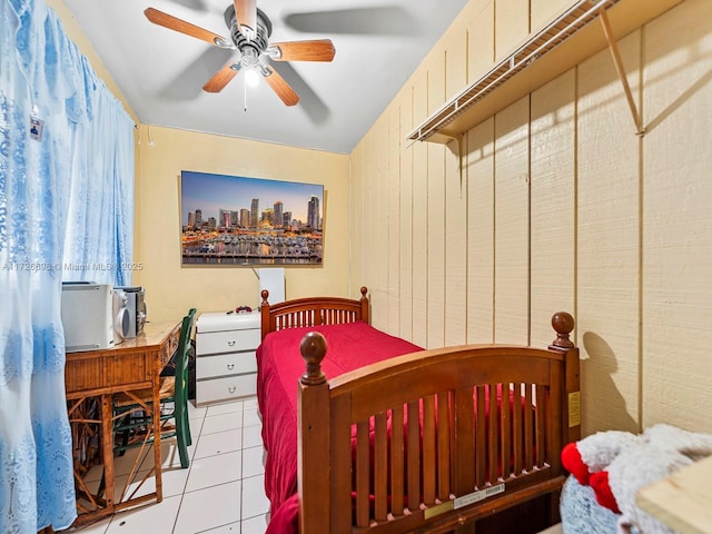 tiled bedroom with ceiling fan and wood walls