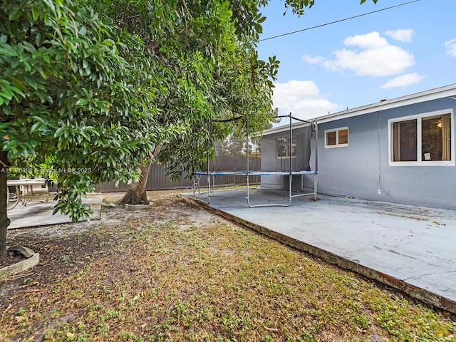 view of yard with a trampoline and a patio area