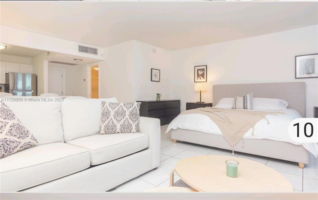 bedroom with light tile patterned floors and stainless steel fridge