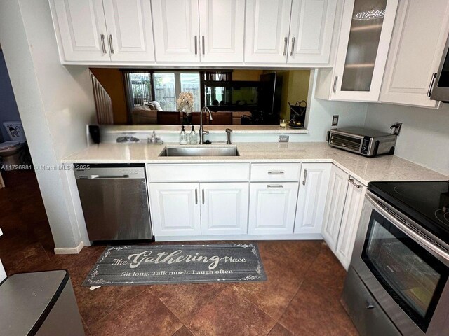 kitchen featuring dark tile patterned floors, stainless steel appliances, white cabinets, and sink