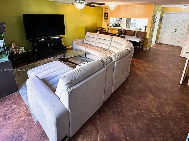 living area featuring a ceiling fan, a textured ceiling, and baseboards