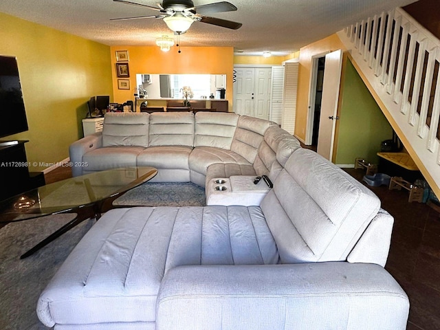 living room with a ceiling fan, a textured ceiling, and stairs