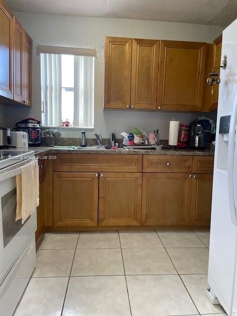 kitchen featuring sink, white appliances, and light tile patterned floors