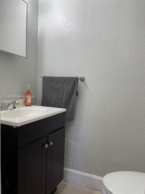 bathroom featuring toilet, vanity, and tile patterned flooring