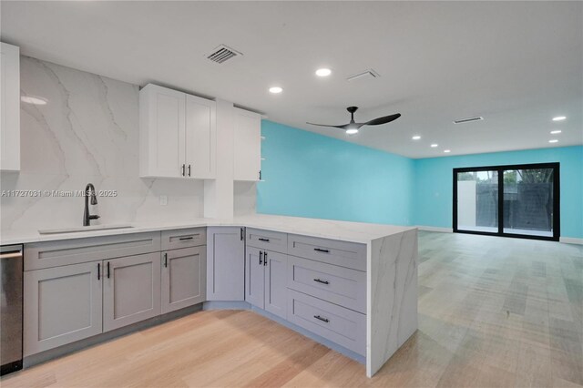 kitchen with white cabinetry, decorative backsplash, sink, kitchen peninsula, and light wood-type flooring