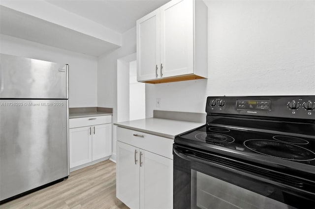 kitchen featuring light hardwood / wood-style floors, black electric range, white cabinets, and stainless steel refrigerator