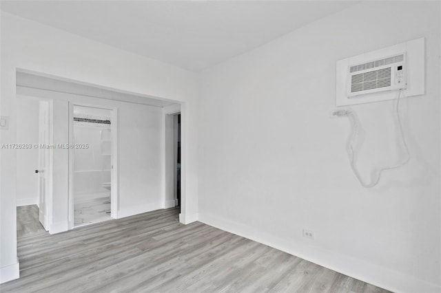 empty room featuring a wall mounted air conditioner and light hardwood / wood-style floors