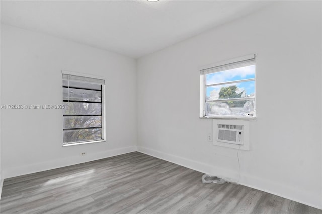 spare room featuring cooling unit, light hardwood / wood-style flooring, and a healthy amount of sunlight