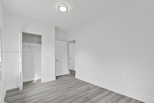 unfurnished bedroom featuring a closet, a textured ceiling, and light hardwood / wood-style flooring