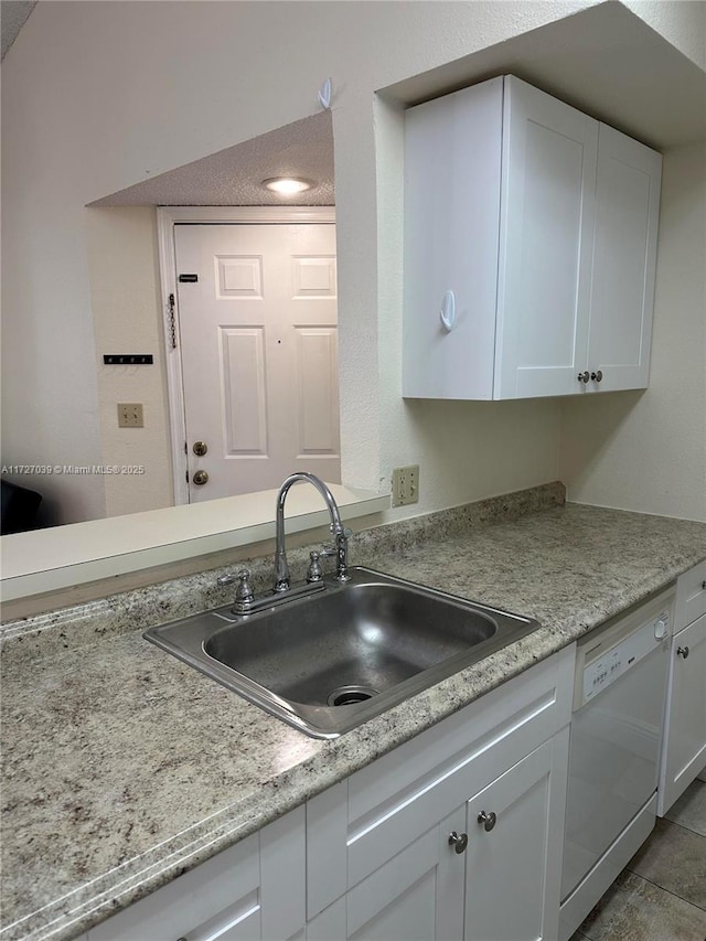 kitchen featuring light tile patterned flooring, white cabinetry, white dishwasher, and sink