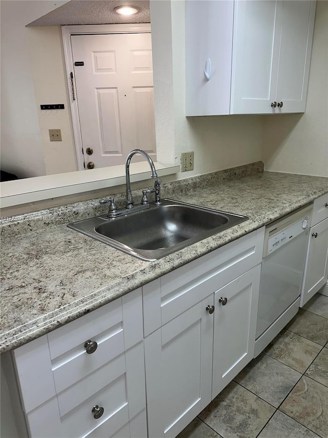 kitchen with light tile patterned floors, dishwasher, sink, and white cabinetry