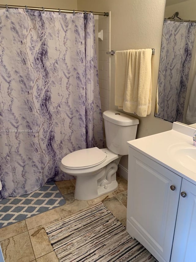 bathroom featuring toilet, vanity, and curtained shower