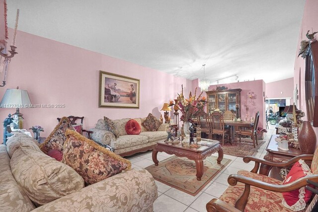 tiled living room featuring lofted ceiling and a notable chandelier