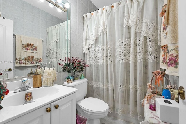 bathroom with toilet, a shower with curtain, tile walls, and vanity