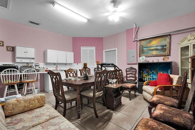 tiled dining room with ceiling fan, a textured ceiling, and electric panel