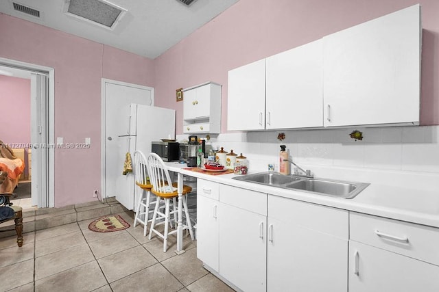 kitchen with light tile patterned floors, sink, and white cabinets