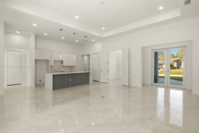 unfurnished living room featuring a high ceiling, sink, and french doors