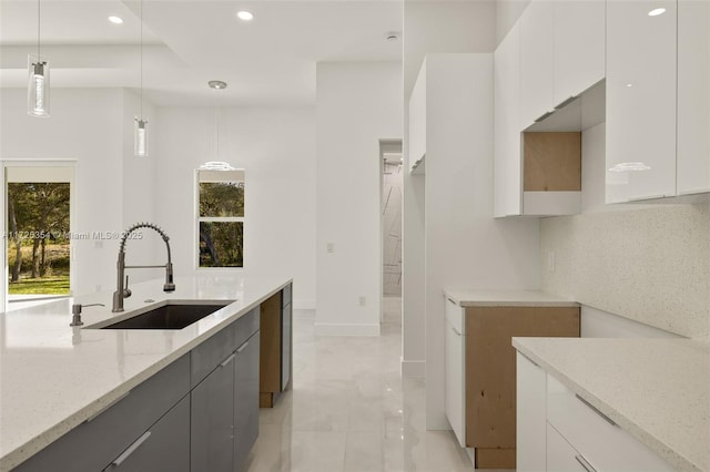 kitchen featuring decorative light fixtures, sink, and white cabinetry