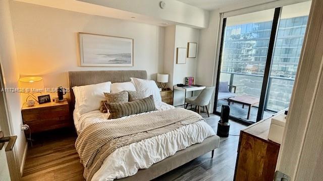 bedroom with access to outside, expansive windows, and hardwood / wood-style flooring