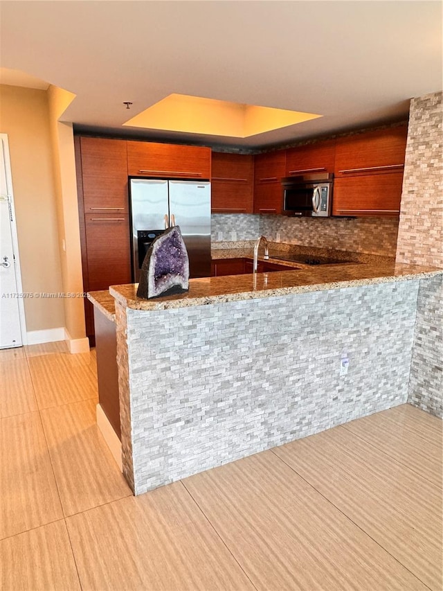 kitchen featuring kitchen peninsula, appliances with stainless steel finishes, decorative backsplash, light tile patterned flooring, and sink