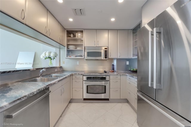 kitchen with light stone countertops, stainless steel appliances, and sink