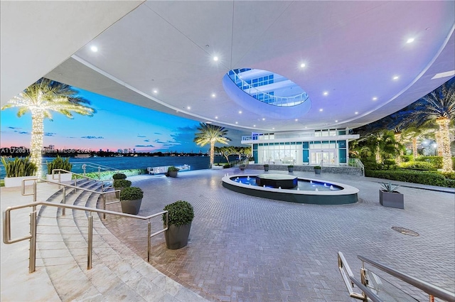 interior space featuring a water view and a swimming pool with hot tub