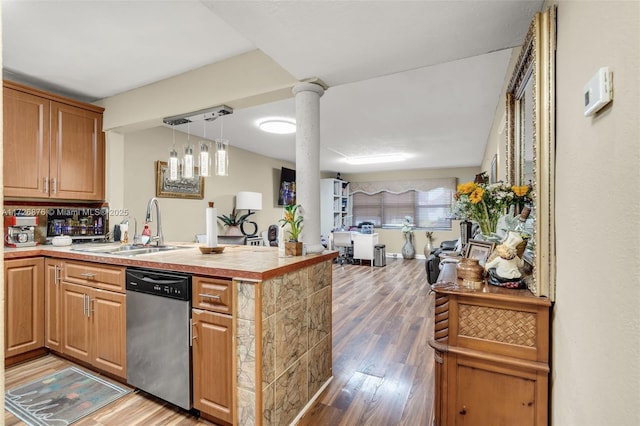 kitchen featuring dishwasher, kitchen peninsula, sink, hardwood / wood-style flooring, and decorative columns