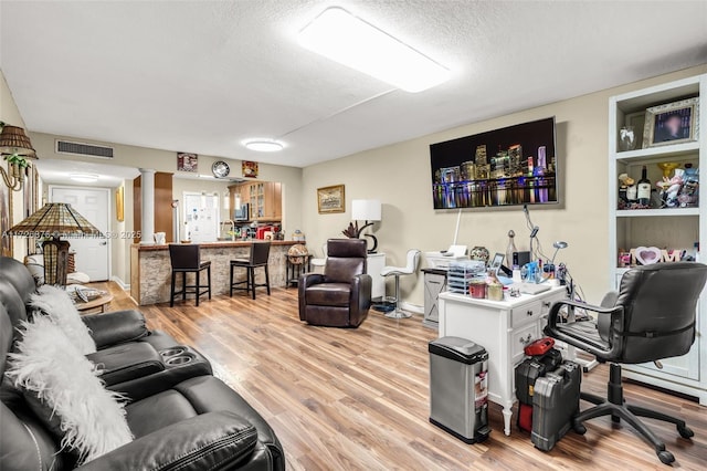 living room with indoor bar, a textured ceiling, and light hardwood / wood-style flooring