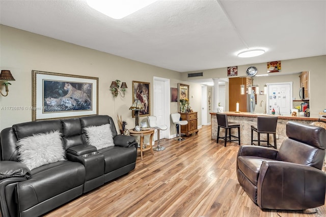 living room featuring a textured ceiling, light hardwood / wood-style flooring, and sink