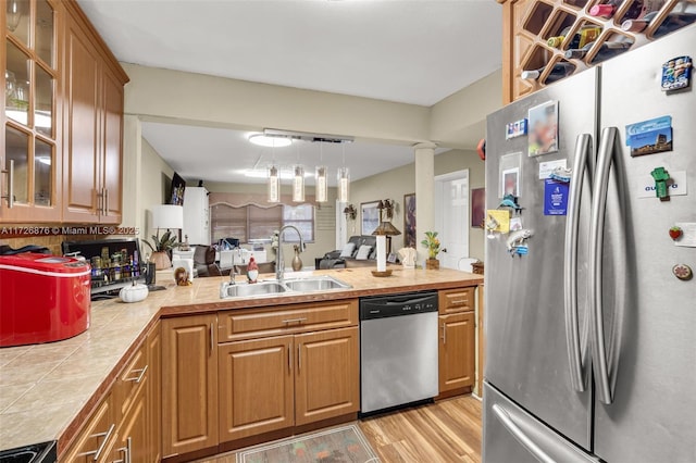 kitchen with sink, hanging light fixtures, stainless steel appliances, and tile countertops