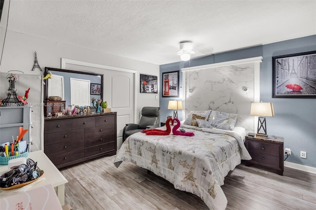 bedroom with ceiling fan, a textured ceiling, and light wood-type flooring