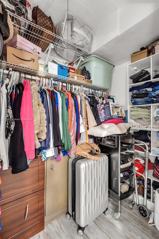 walk in closet with light hardwood / wood-style floors