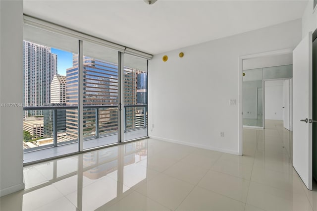 tiled empty room featuring a wall of windows