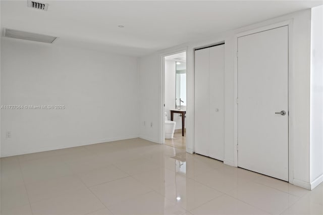 unfurnished bedroom with light tile patterned floors and ensuite bath