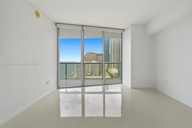 tiled spare room featuring a water view and a wall of windows