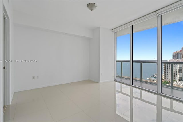 tiled spare room with a wall of windows, a water view, and a wealth of natural light