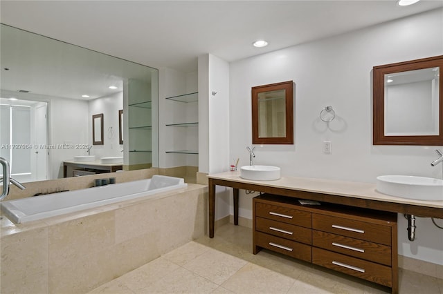 bathroom featuring a relaxing tiled tub, vanity, and tile patterned flooring