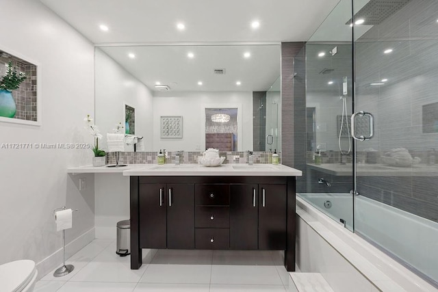 full bathroom with tile patterned flooring, vanity, decorative backsplash, bath / shower combo with glass door, and toilet