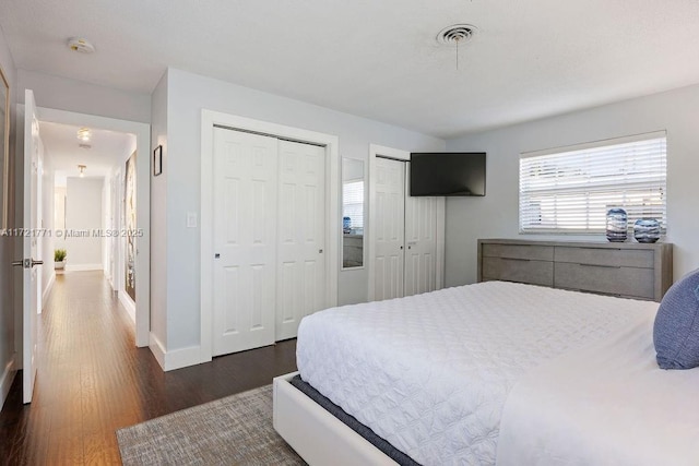 bedroom featuring multiple closets and dark wood-type flooring