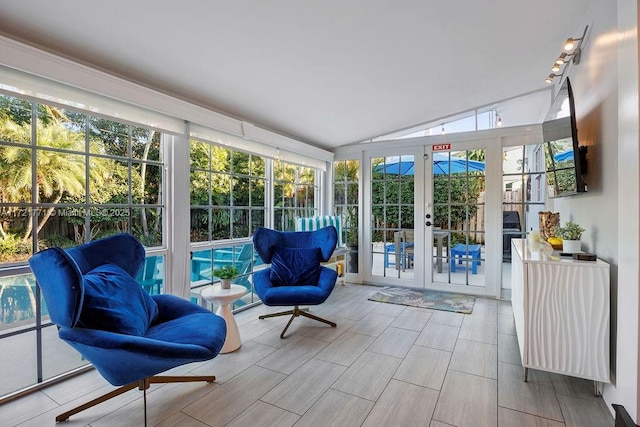 sunroom with plenty of natural light, lofted ceiling, and french doors