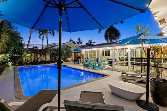 pool at dusk with an outbuilding and a patio