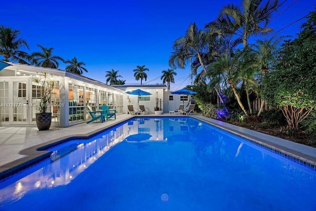 pool at dusk featuring a patio